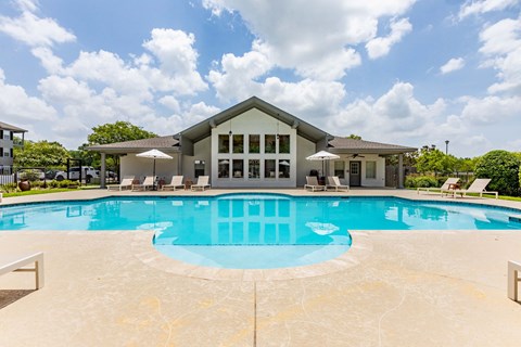 a large swimming pool with a house in the background
